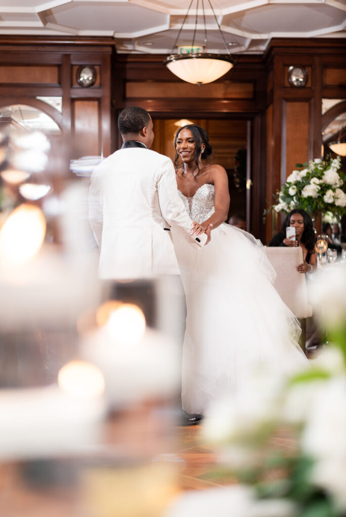 bride and groom dancing together at their indoor wedding reception at hotel crescent in Dallas with dark wood walls decorated with white florals