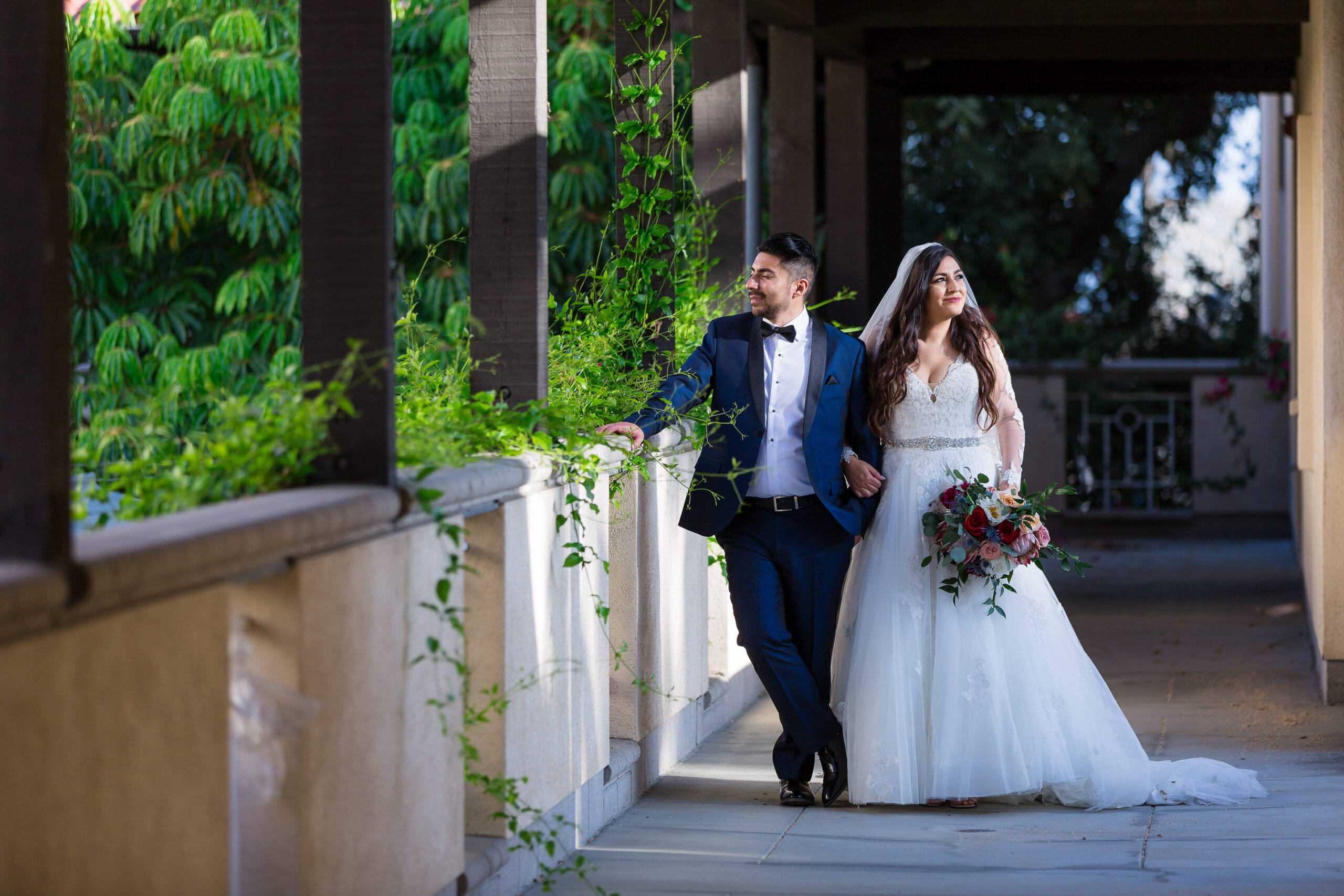 dallas wedding photographers captures bride and groom standing in a corridor together with green vines creeping in from the garden for their dallas wedding photography