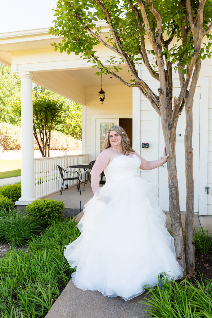 Bride standing by tree in wedding dress at the Milestone wedding venue in Denton