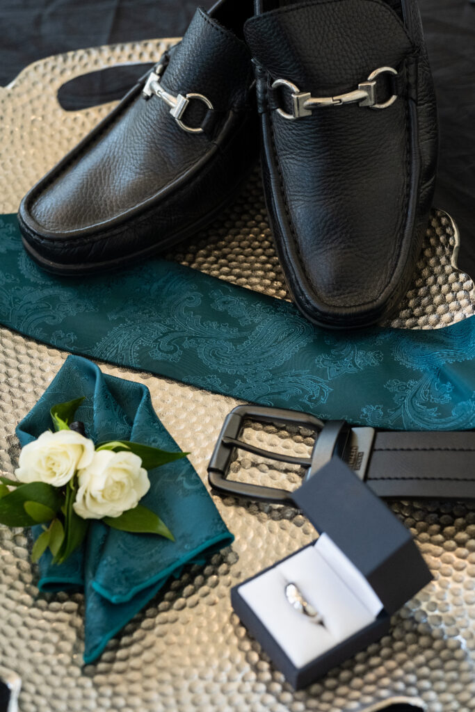 Groom's wedding details including shoes, tie, ring, belt and boutonniere 