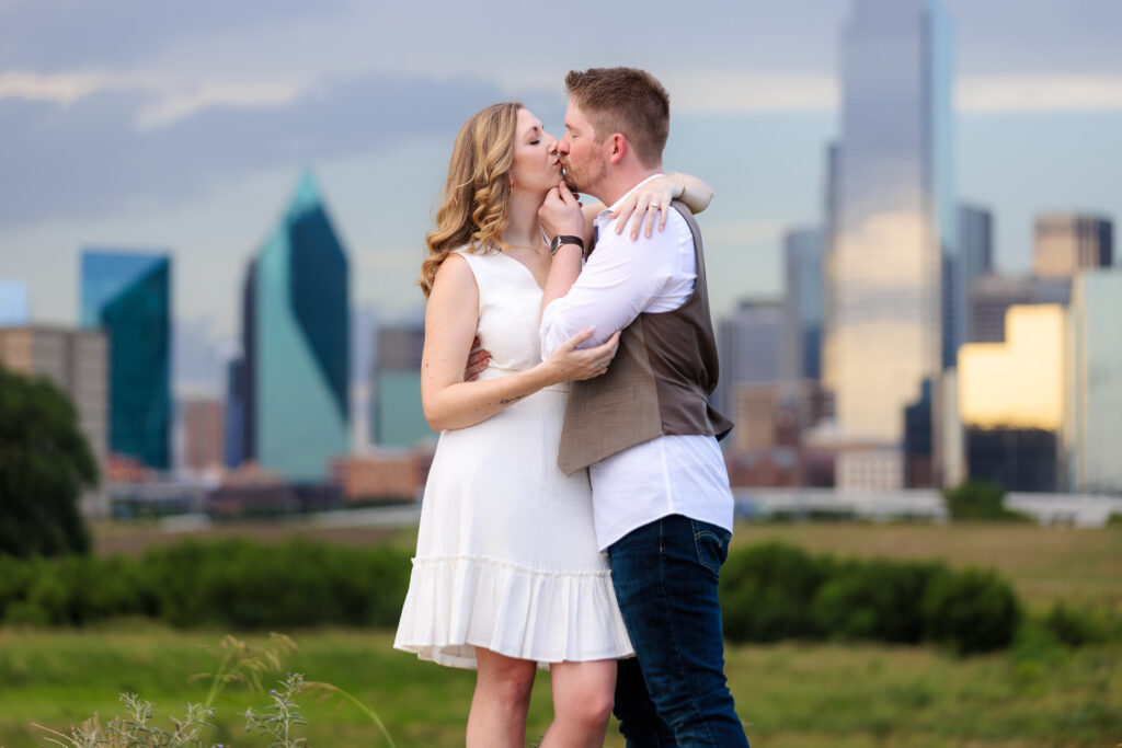 Dallas wedding photographers capture man holding woman's chin while kissing at Trinity Overlook Park