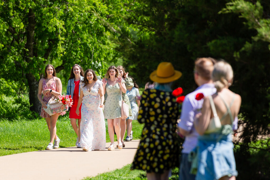 Dallas wedding photographers capture woman walking with friends to people holding flowers