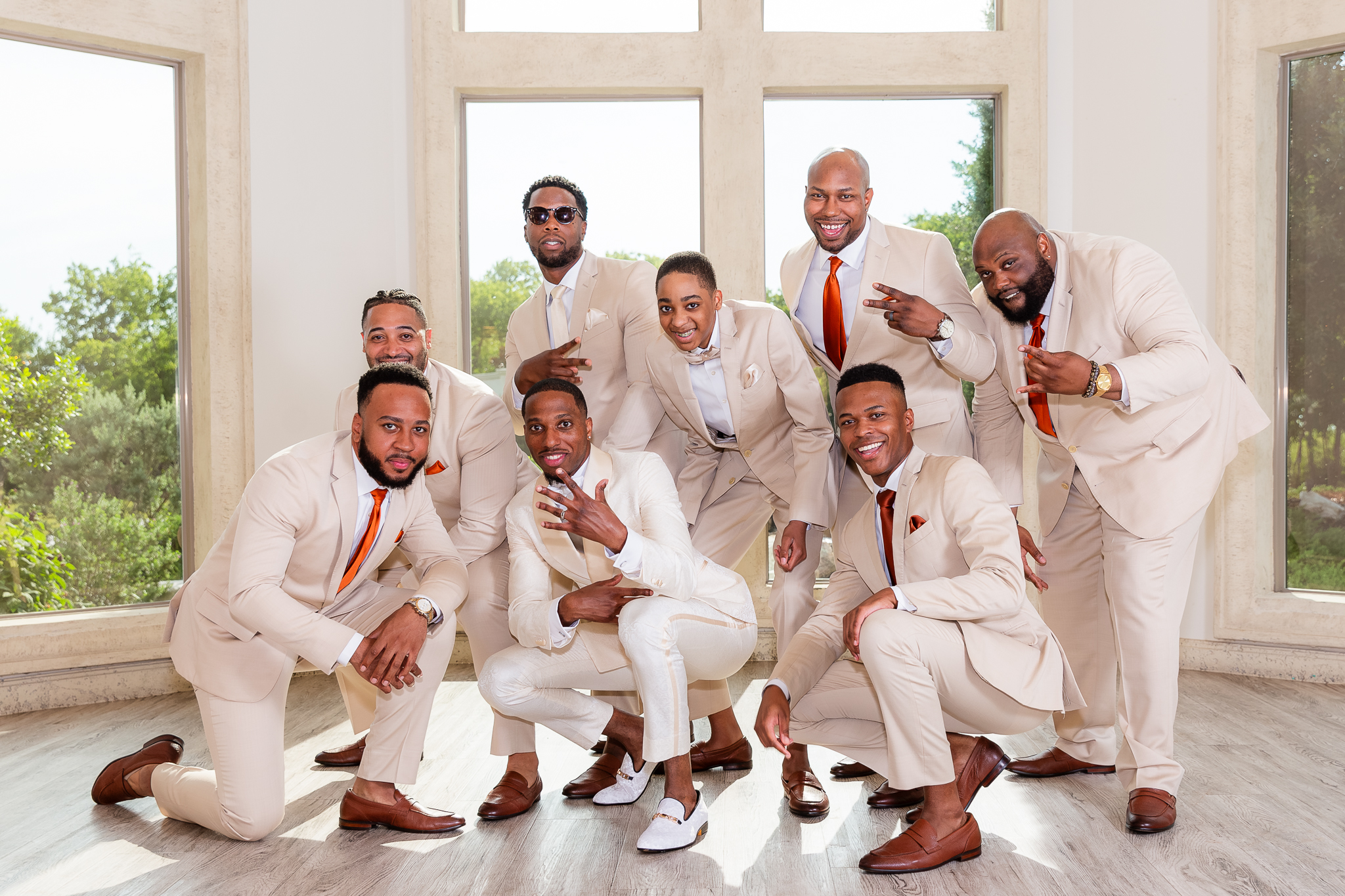 grom with groomsmen in beige suits kneeling and smiling at knotting hill place wedding venue in little elm texas by dallas wedding photographer Stefani Ciotti Photography