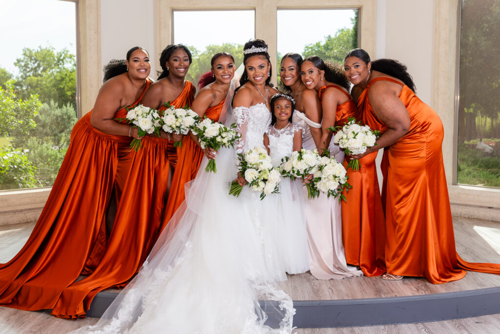 Bridal party in orange smiling at camera in Knotting Hill Place ceremony space