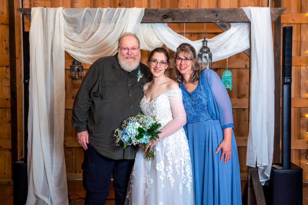 Dallas wedding photographers capture bride holding bouquet standing with parents