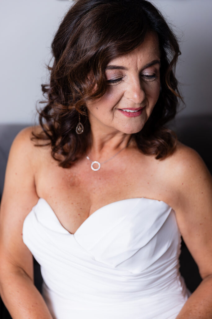 Bride looking down and smiling on couch in Stoney Ridge Villa bridal suite