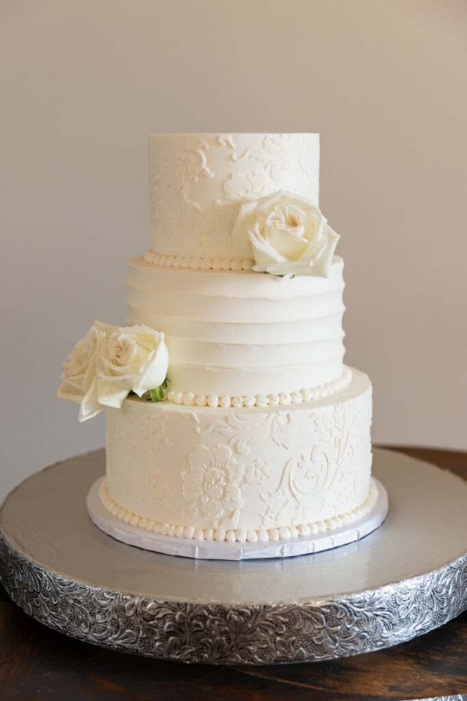 Dallas wedding photographer captures wedding cake with three tiers with flowers