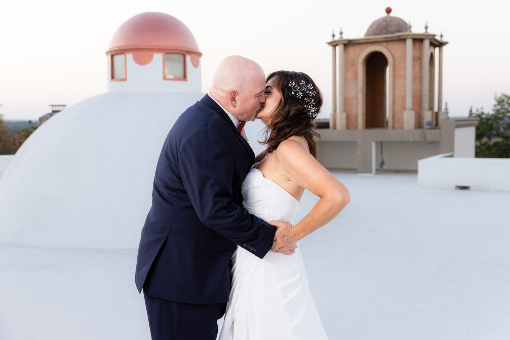 Bride and groom kissing on rooftop of Stoney Ridge Villa wedding venue in Azle Texas