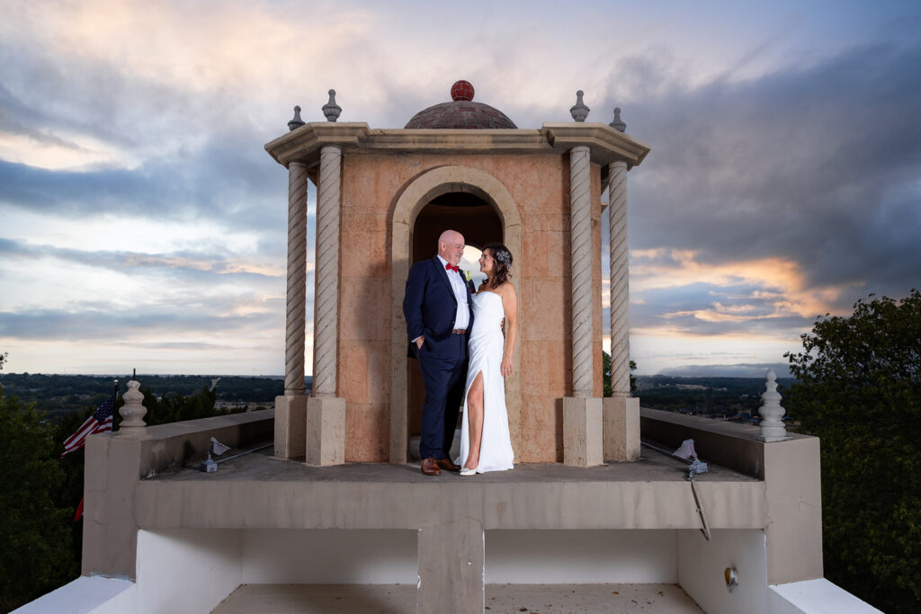 Dallas wedding photographer Stefani Ciotti Photography captures couple in wedding attire standing on top of wedding venue Stoney Ridge Villa in Azle TX at sunset
