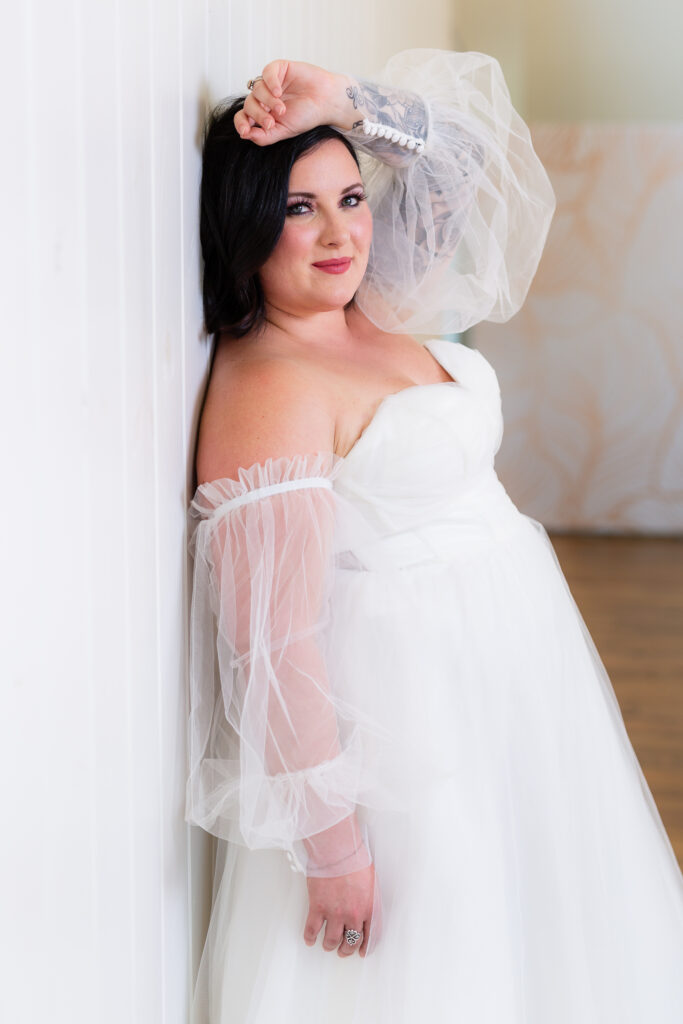 Bride leaning against wall in strapless wedding gown with big puff sleeves