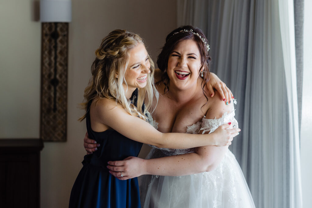 bride and sister hugging and laughing in Sandals hotel during wedding preparation