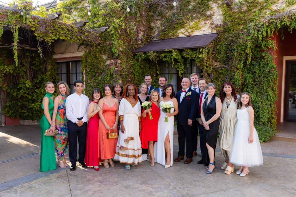 Formal photo of wedding party smiling with bride and groom after ceremony in Stoney Ridge Villa's courtyard in Azle, TX