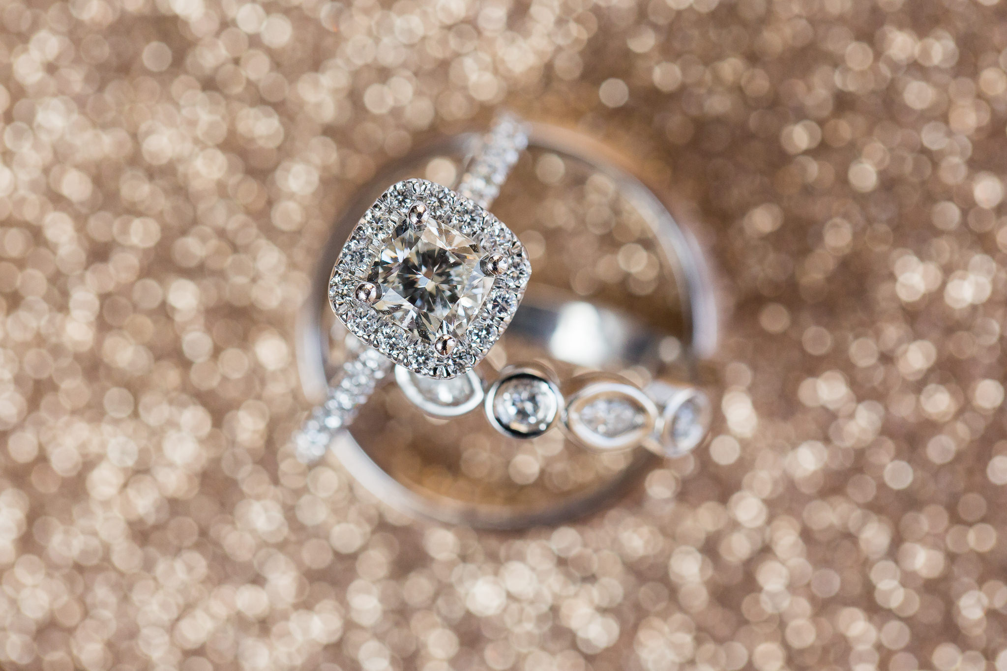 Square halo diamond engagement ring and bezel wedding ring set on glittery gold