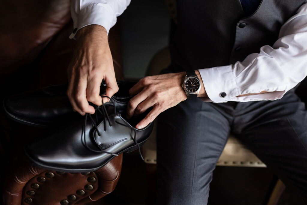 Groom lacing up black wedding shoes