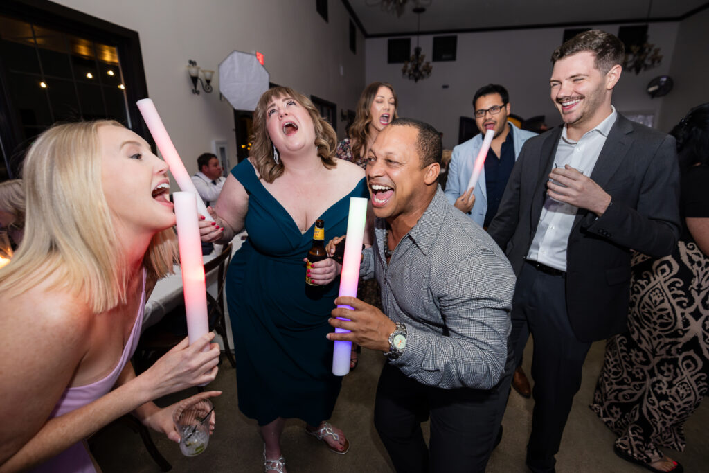 Guests dancing and singing on dance floor during wedding reception