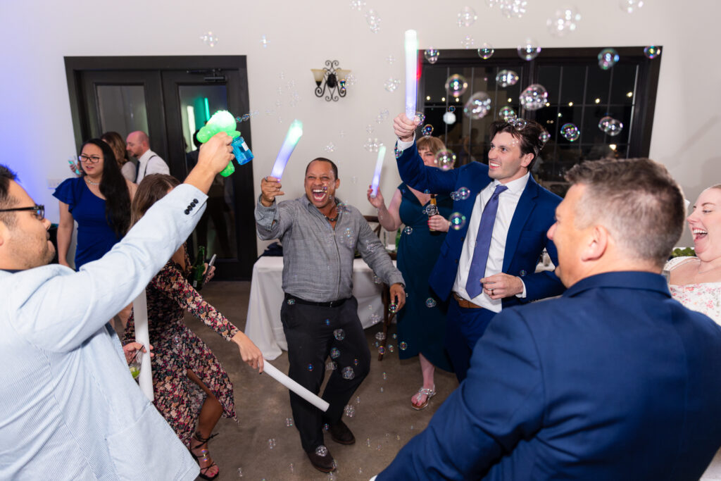 Wedding guests dancing and playing with LED glow sticks and bubble guns