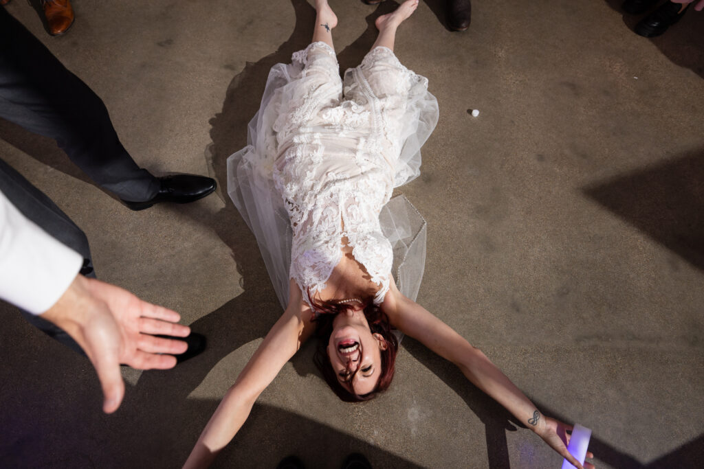 Bride laying sprawled out on the dance floor laughing