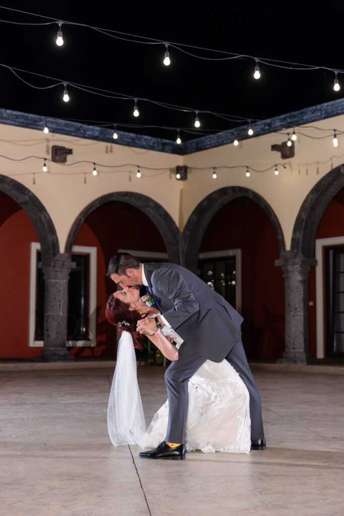 Bride and groom dipping and kissing during private last dance in courtyard of Azle TX wedding villa