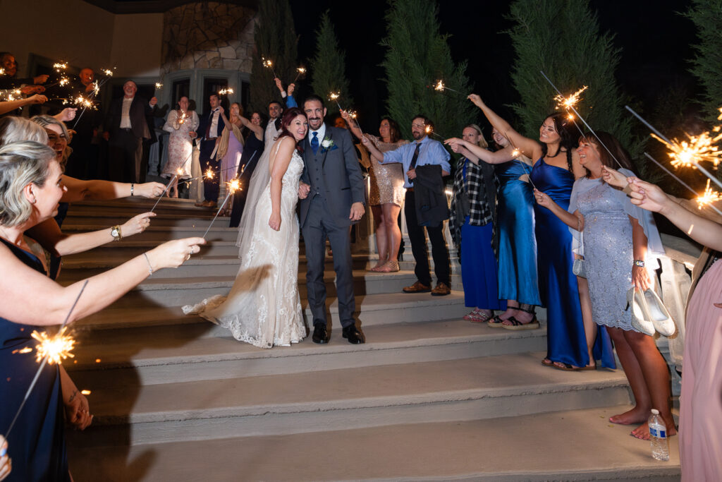 Bride and groom smiling and walking down staircase during sparkler exit