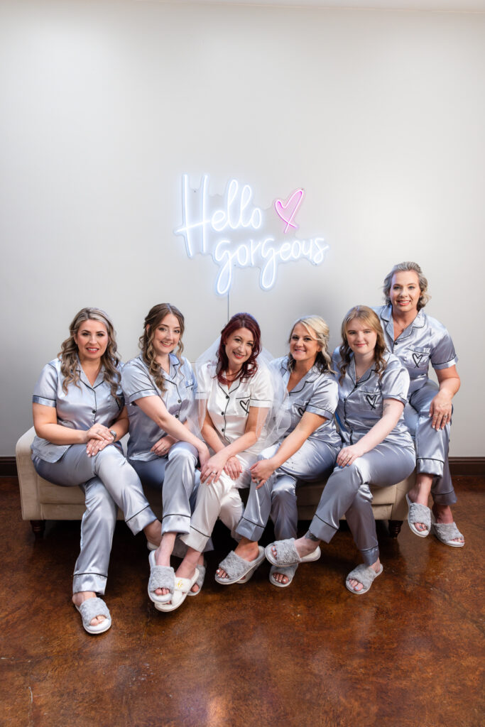 Bride and bridesmaids in wedding pjs in Azle wedding venue bridal suite with hello gorgeous sign on the wall