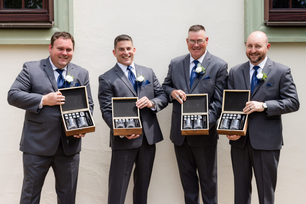 Groomsmen opening gift boxes of whiskey glasses