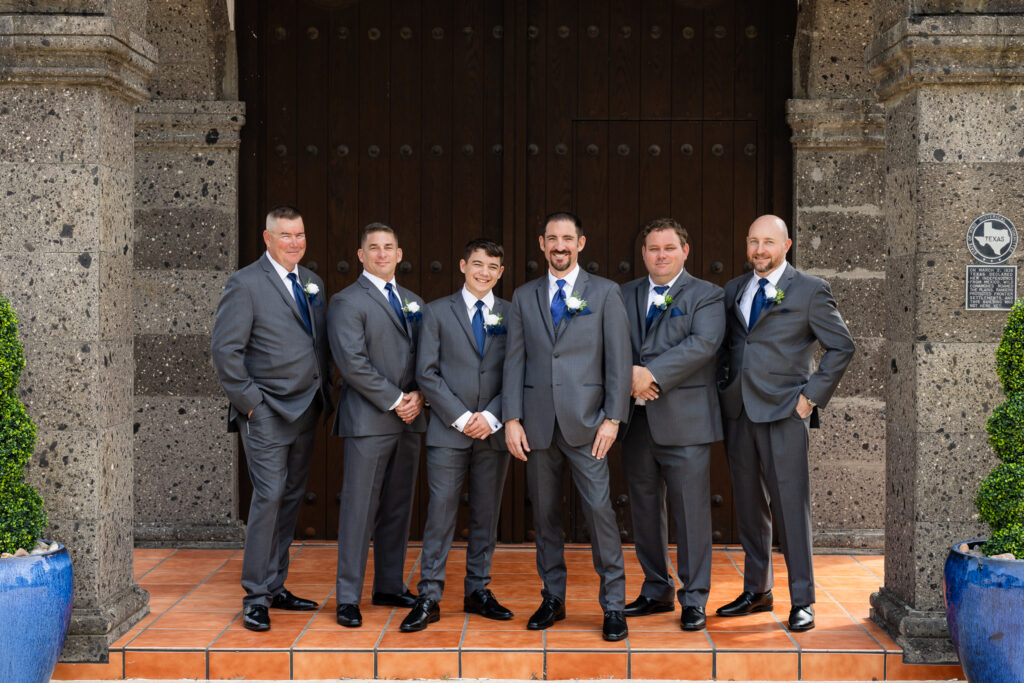 Groomsmen smiling at entrance to Azle TX wedding villa