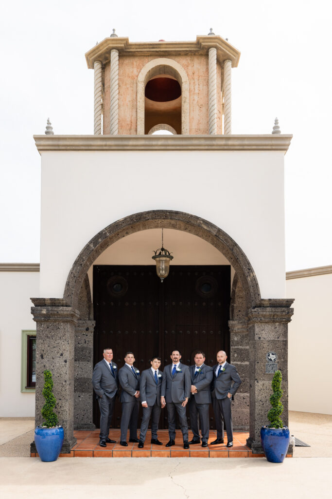 Groom and groomsmen smiling in front of Azle TX wedding venue Stoney Ridge Villa