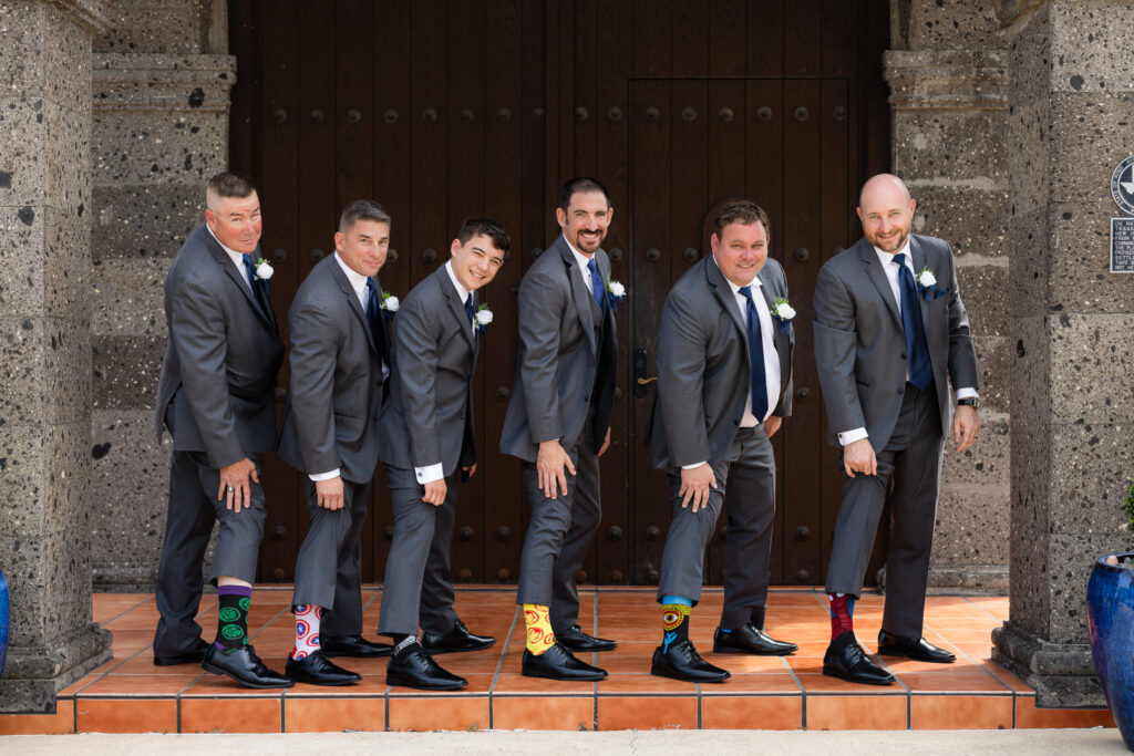 Groomsmen holding up pant legs to showcase Marvel socks