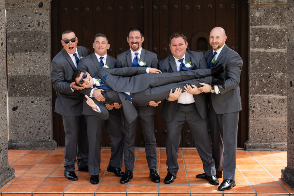 Groomsmen holding up groom's son laughing