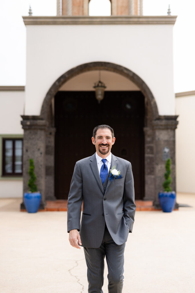 Groom smiling and walking in front of Azle TX wedding venue Stoney Ridge Villa