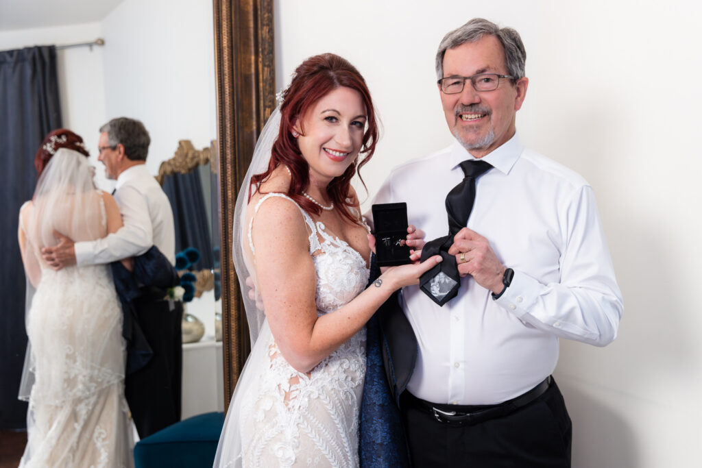 Bride and dad holding tie and cufflinks smiling