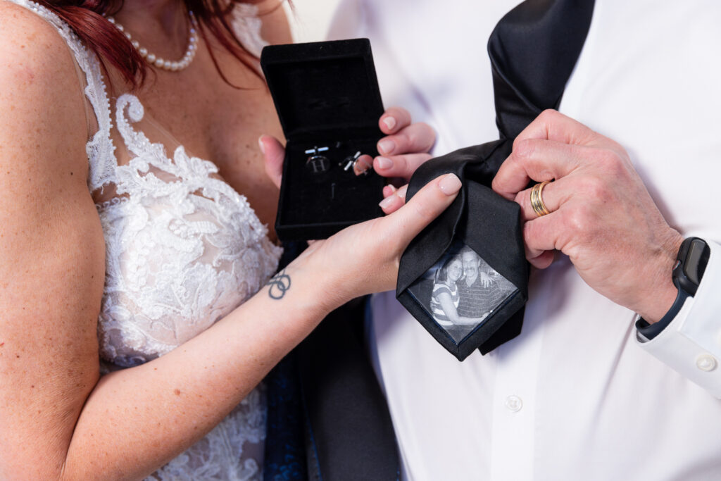 Bride and dad holding tie gift with old photo on the back of tie