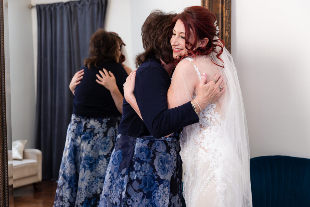 Bride hugging mom in front of large mirror in Stoney Ridge Villa bridal suite in Azle TX