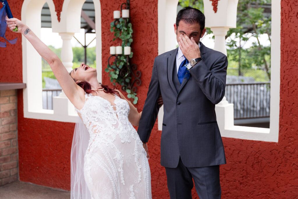 Bride celebrating and throwing bouquet in air while groom wipes tears