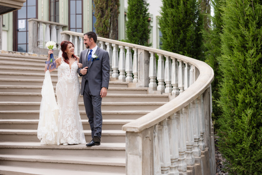 Bride and groom walking down grand staircase smiling at each other