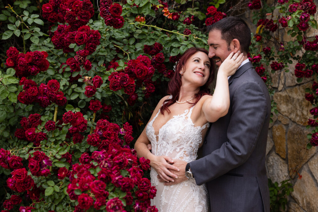 Bride smiling up at groom in red roses at Stoney Ridge Villa wedding venue in Azle TX