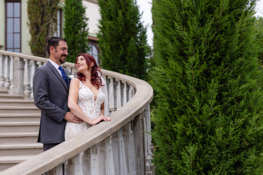 Bride and groom smiling and laughing at each other on grand staircase at Stoney Ridge Villa in Azle TX