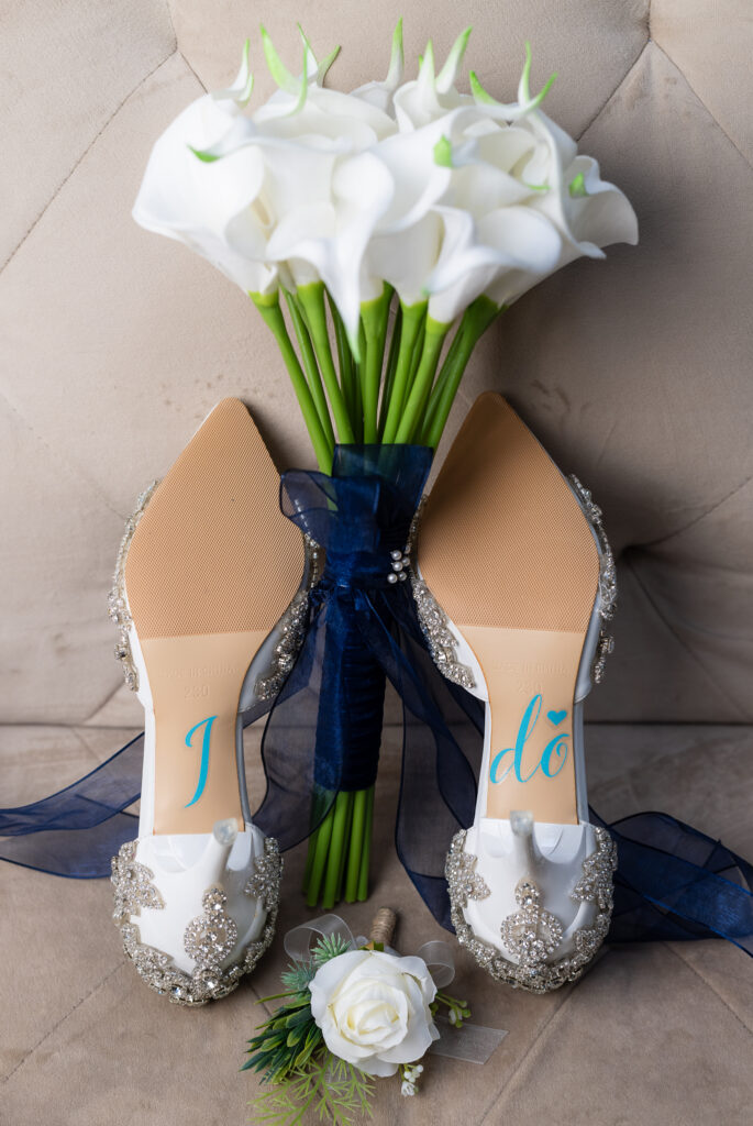 Wedding shoes with I Do decals on the back and a white tulip bouquet in the middle