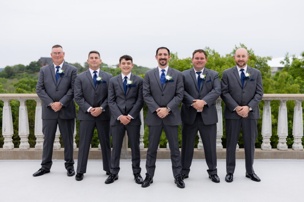 Groom and groomsmen in blue suits and blue ties smiling