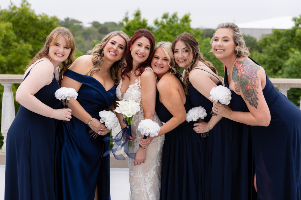 Bridesmaids in blue dresses smiling and leaning into bride smiling