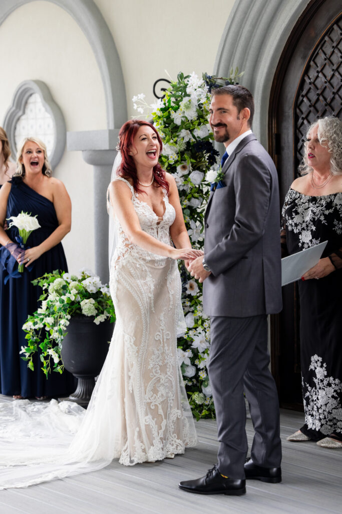 Bride laughing at groom while holding hands during wedding ceremony