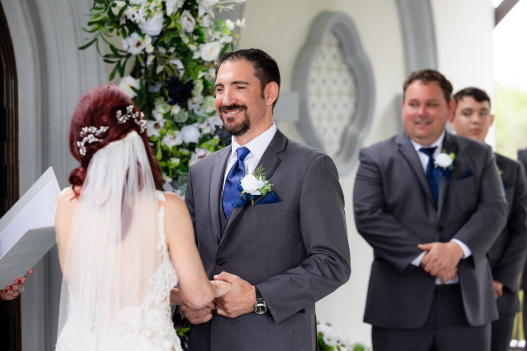 Groom smiling and holding hands with bride