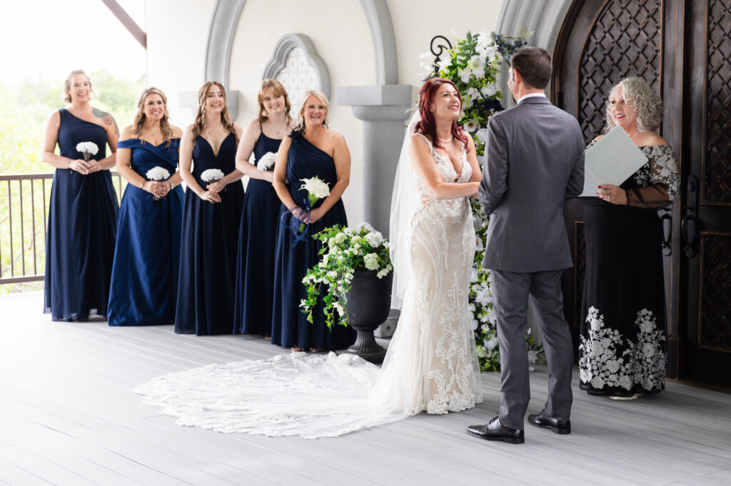 Bride and groom holding hands smiling while officiant and bridesmaids smile