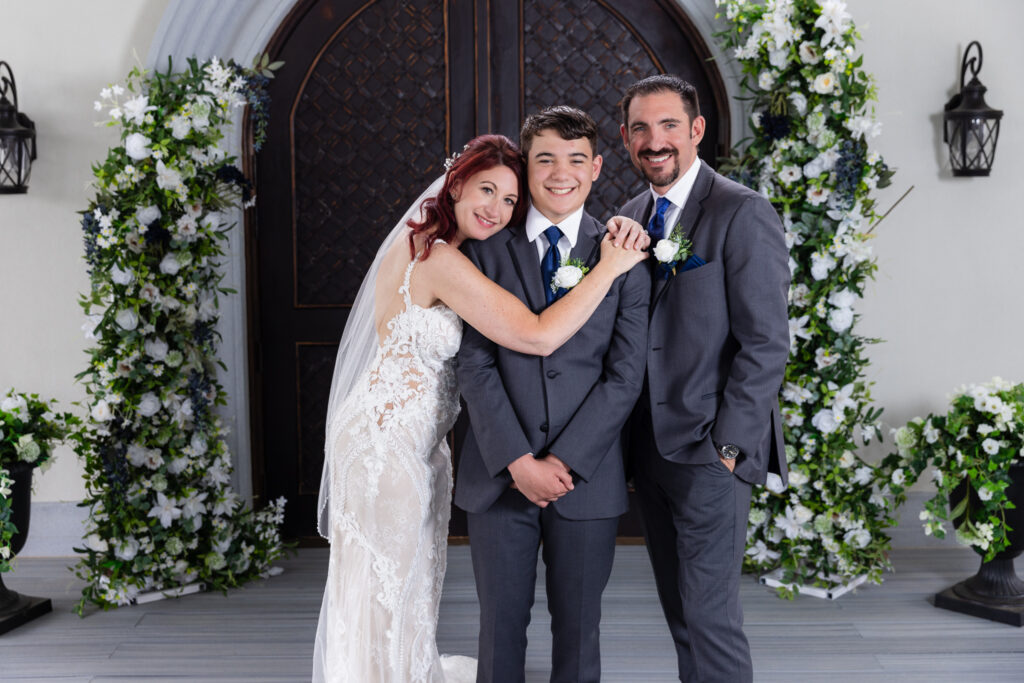 Bride and groom hugging son at ceremony site at Stoney Ridge Villa covered ceremony space