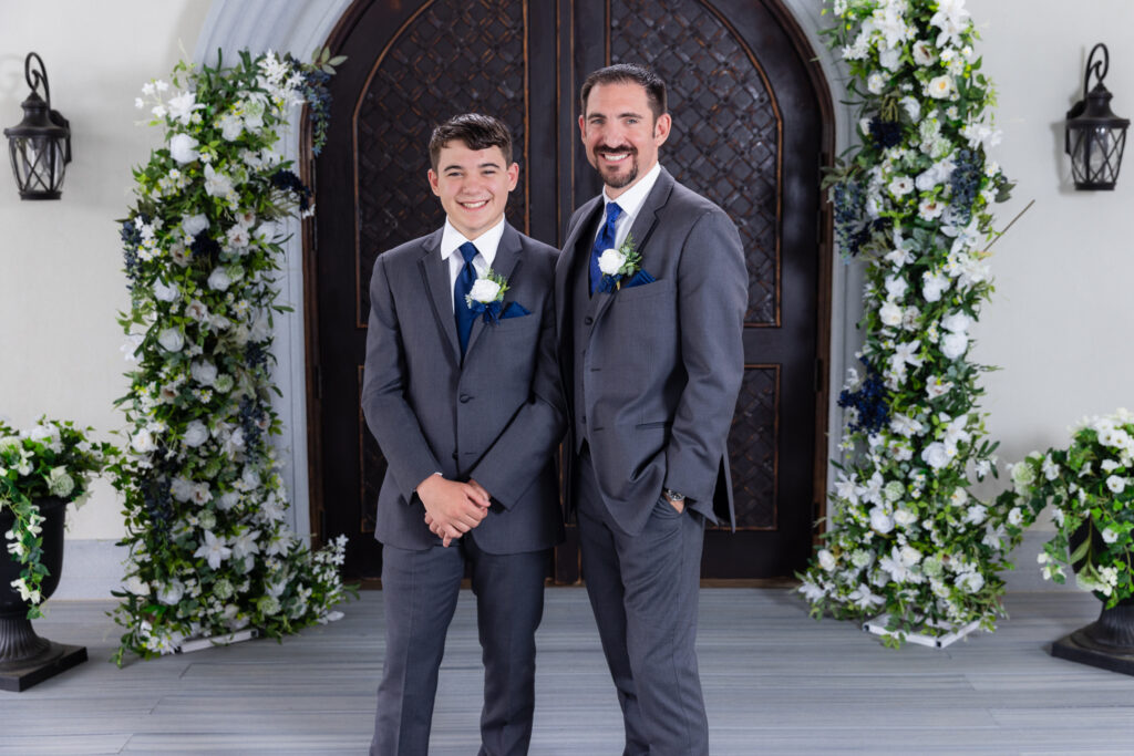 Groom smiling with son in suits