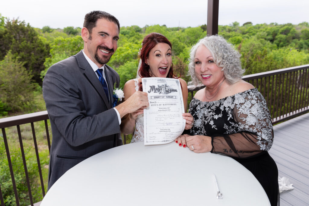 Bride and groom excitedly holding up marriage license with officiant