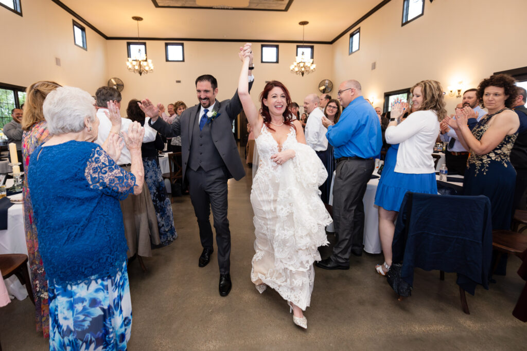 Bride and groom holding hands and smiling as they enter their wedding reception