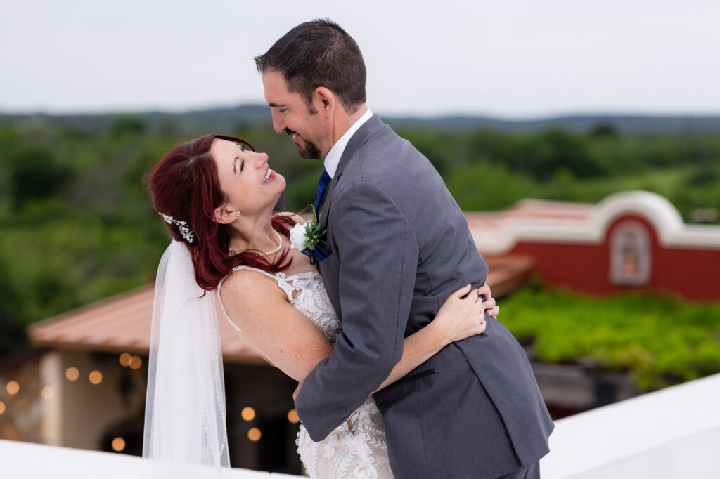 Bride and groom laughing at each other on rooftop of Azle TX wedding venue