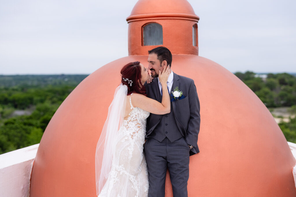 Red-haired bride intimately smiling at groom in grey suit laughs at her