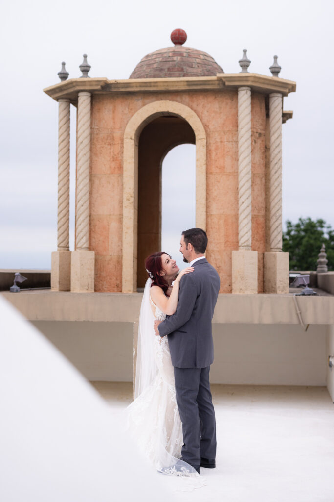 Bride and groom dancing on wedding venue rooftop near bell tower